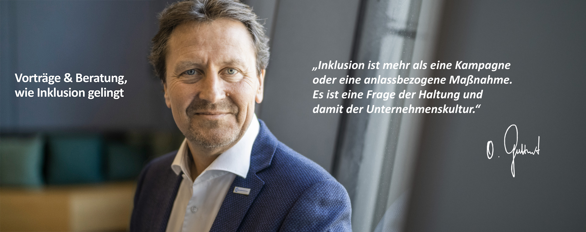 Olaf Guttzeit ist frontal und lächelnd zu sehen. Er trägt einen blauen Blazer und ein Hemd. Am Revers ist die Anstecknadel des „UnternehmensForums“ zu sehen. Daneben steht folgendes Zitat: „Inklusion ist mehr als eine Kampagne oder eine anlassbezogene Maßnahme. Es ist eine Frage der Haltung und damit der Unternehmenskultur.“